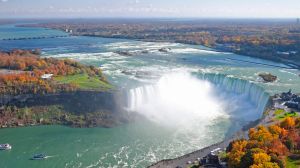 Horseshoe Falls of Niagara with brilliant fall colors and floating white clouds.