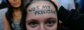 Clair Sheehan has the words "Not My President" written on her forehead as she takes part in a protest against the ...