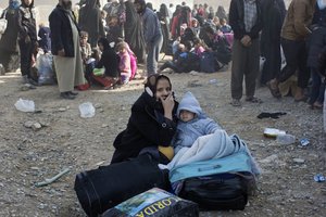 People take shelter behind a house as mortars land in their proximity in Gogjali, on the eastern edges of Mosul, Iraq, Sunday, Nov. 6, 2016.