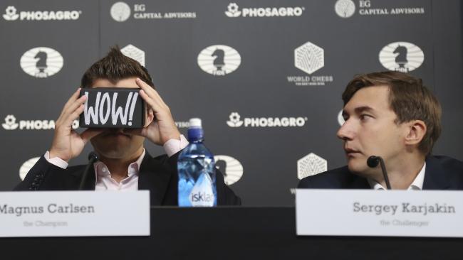 Chess world champion Magnus Carlsen, of Norway, left, looks through a virtual reality viewer while his challenger, Sergey Karjakin, of Russia, looks on.