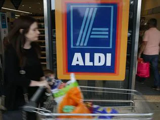 A woman pushes a shoping trolley past an Aldi logo as she leaves one of the company's supermarket stores in London on September 26, 2016. Aldi UK announced on Monday that it will invest £300 million ($389 million, 346 million euros) to revamp its stores over the next three years. Aldi and its German rival Lidl have boomed in Britain, grabbing market share from traditional supermarkets Asda, Morrison, Sainsbury's and Tesco, as customers tightened their belts to save cash. / AFP PHOTO / Daniel Leal-Olivas