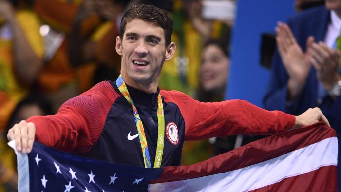 USA's gold medallist Michael Phelps holds the US flag after the podium ceremony of the Men's swimming 4 x 100m Medley Relay Final at the Rio 2016 Olympic Games at the Olympic Aquatics Stadium in Rio de Janeiro on August 13, 2016. / AFP PHOTO / Martin BUREAU