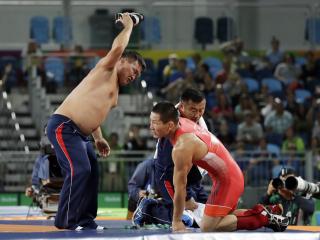 Coaches for Mongolia's Mandakhnaran Ganzori, at right, strip in protest after a loss to Uzbekistan's Ikhtiyor Navruzov during the men's 65-kg freestyle bronze medal wrestling match at the 2016 Summer Olympics in Rio de Janeiro, Brazil, Saturday, Aug. 20, 2016. (AP Photo/Marcio Jose Sanchez)