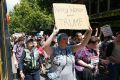 Protesters against Donald Trump walk along Swanston Street stopping trams. 