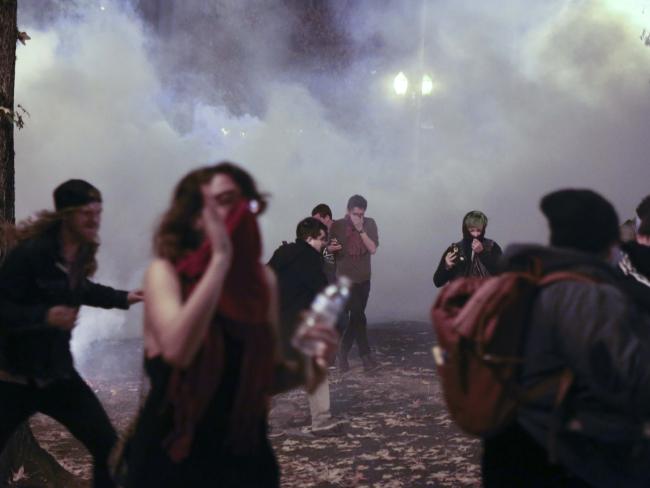 Demonstrators protesting the election of President-elect, Donald Trump in Portland, oregon, flee as police use tear gas and flash-bang grenades. Picture: Stephanie Yao Long / The Oregonian via AP