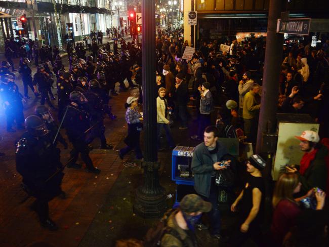 Police wearing riot gear watch as demonstrators protest against Donald Trump's US presidential election victory, at City Hall in Portland. Picture: AFP / Ankur Dholakia