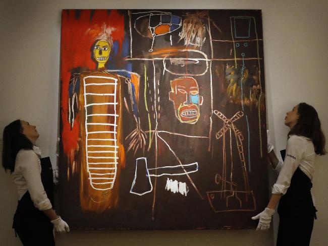 Two workers from Sotheby’s lift Basquiat’s 
<i>Air Power </i>artwork which just sold for 7.1 million pounds.