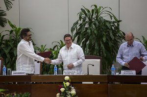 Ivan Marquez, chief negotiator of the Revolutionary Armed Forces of Colombia (FARC), left, shakes hands with Cuba's Foreign Minister Bruno Rodriguez, center, standing next to Humberto de La Calle, head of Colombia's government peace negotiation team, after the signing of the latest and definitive text of the peace accord between the two sides in Havana, Cuba, Saturday, Nov. 12, 2016.