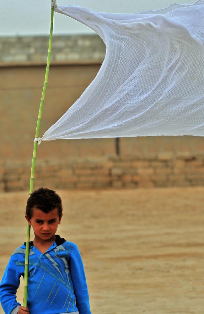 An Iraqi boy who was displaced from the village of Abu Shuwayhah, south of the jihadist-held Mosul, carries a white flag. The Islamic State is trying to recruit boys to fight. Picture: AFP/Ahmad Al-Rubaye