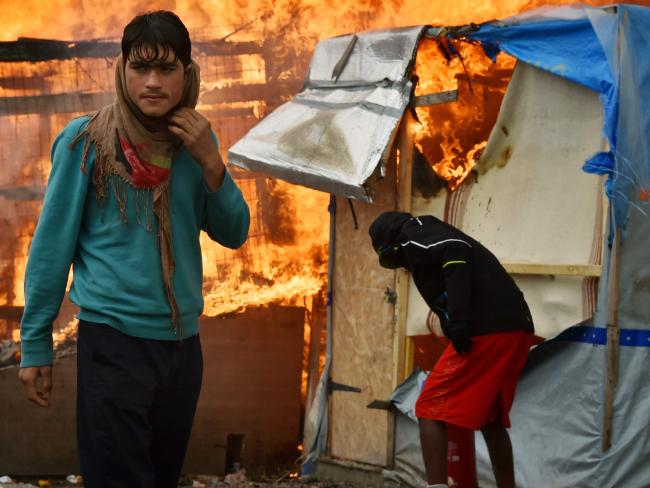 A migrant looks on as a makeshift shelter burns behind him at the &quot;jungle&quot; migrant camp in Calais, northern France. Picture: AFP