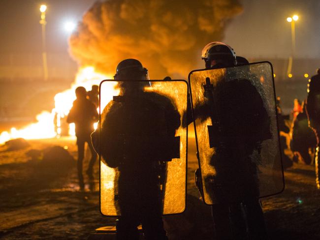 A portable chemical toilet burns as French riot police advance towards the Jungle migrant camp. Picture: Jack Taylor/Getty Images.