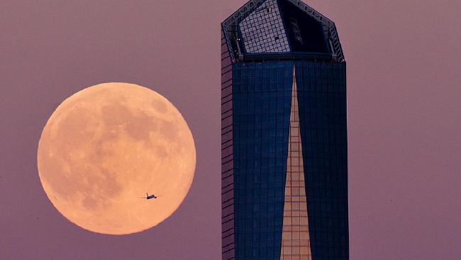 A plane flights across the supermoon surrounded by a Madrid skyscraper on August 9, 2014 in Madrid, Spain.