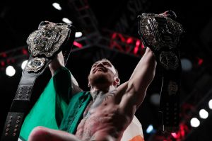 Conor McGregor holds up his title belts.