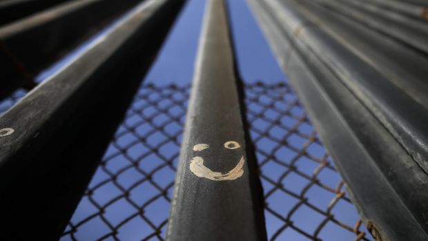 Graffiti adorns metal bars marking the United States border where it meets the Pacific Ocean.