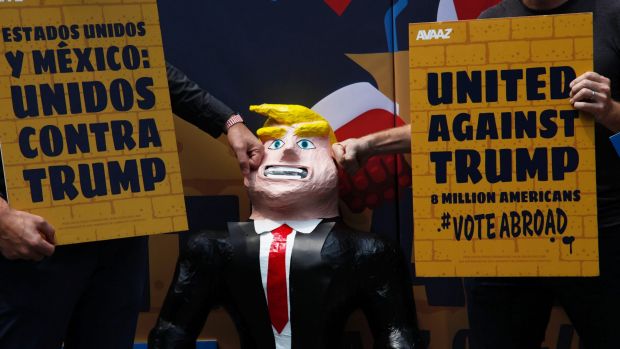 A couple of men hit a pinata representing US Republican presidential candidate Donald Trump leaning against a symbolic ...