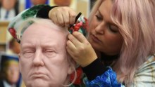 A woman works on a wax figurine of president-elect donald trump.
