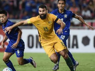 Australian player Mile Jedniak (C) controls the the ball past Thailand players during the 2018 World Cup football qualifying match between Thailand and Australia in Bangkok on November 15, 2016. / AFP PHOTO / LILLIAN SUWANRUMPHA