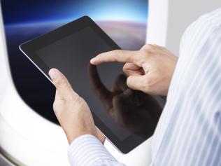 Businessman holding digital tablet in airplane