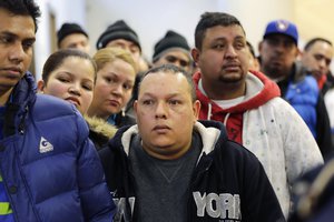 FILE - In this Jan. 12, 2015 file photo, people wait in line to apply for municipal identification cards on the first day they were available at the Bronx Library Center, in the Bronx borough of New York.