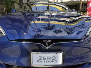 FILE - In this Oct. 24, 2016, file photo, palm trees are reflected on the hood of a Tesla Model S on display in downtown Los Angeles. Lower-income buyers of electric cars will get a bigger break under California's newest rebate rules, while deals for higher earners will disappear. Changes to the state's Clean Vehicle Rebate Project went into effect this week for buyers of all-electric, plug-in hybrid and fuel-cell cars. (AP Photo/Richard Vogel, File)