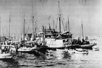 An old black-and-white photo of a large pearling lugger surrounding by smaller boats.