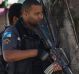 Police on an anti-drug trafficking operation patrol as a woman pushes a child along the sidewalk in the Cidade de Deus ...