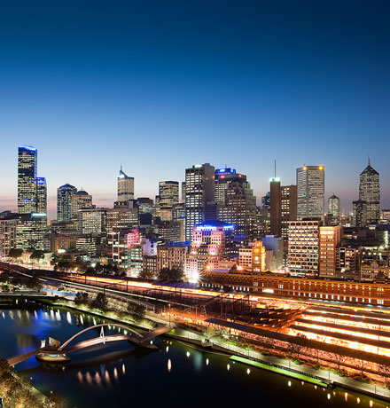 Melbourne at night from afar. The sky is darkening and the city's lights are on.