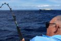 Merimbula Big Game and Lakes Angling Club secretary Chris Young fishes with the Geelong Star trawler in the background.