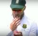 Faf du Plessis seen rubbing the ball with a mint in his mouth.