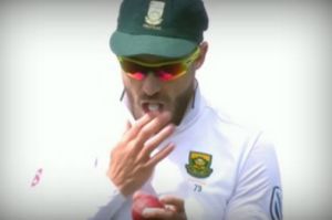 Faf du Plessis seen rubbing the ball with a mint in his mouth.