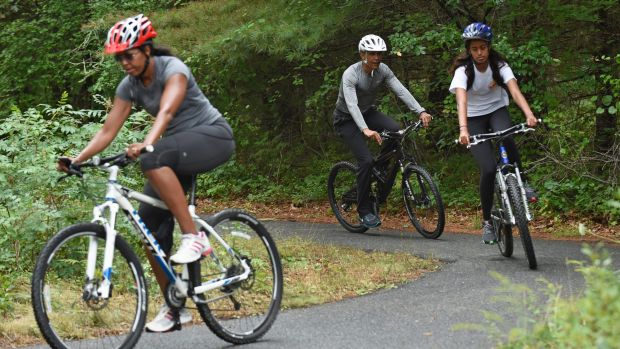 From left: Michelle Obama, Barack Obama and their eldest daughter Malia ride their bikes while on holidays in August.