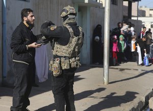 An Iraqi special forces soldier, right, speaks with a civilian man as they coordinate the fleeing of civilian people at an al-Tahrir front line neighborhood in Mosul city, Iraq, Sunday, Nov. 20, 2016.