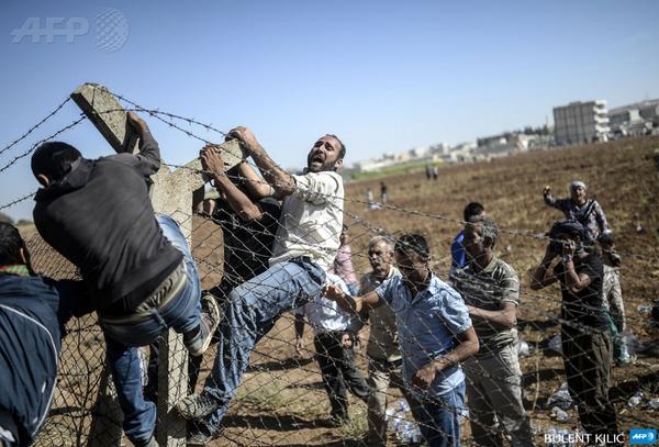 Turkish and Syrian Kurds tear down the border fence to cross into Kobane in neighboring Syria. Photo:AFP