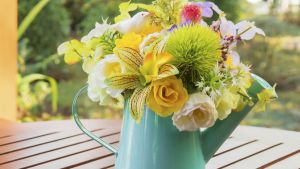 Bouquet of flowers in watering can on wooden table a day to remember