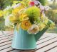 Bouquet of flowers in watering can on wooden table a day to remember