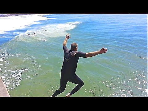 Surfer jumps off Huntington Beach Pier CA.  3-8-2016