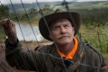 Kevin Sanders at one of the fences he built to keep deer out of his apple orchard. 