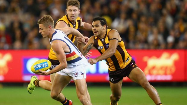 Hawthorn's Cyril Rioli  hangs on to David Mackay of the Crows.