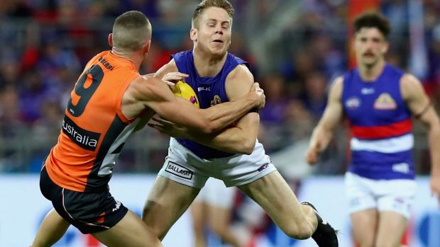 Giving it everything: Lachie Hunter of the Bulldogs is tackled by Tom Scully of the Giants.