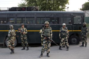 Indian security personnel stand guard near the damaged bus which was ambushed by rebels in Bijbehara, 45 Kilometers (28 miles) south of Srinagar, Indian controlled Kashmir, Friday, June 3, 2016.