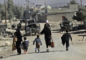 Iraqi citizens fleeing the fighting between Iraqi forces and Islamic State militants, carry their belongings as they arrive to a gathering point where the Iraqi army transfers people from the the front line villages to refugee camps, in the Al-Samah neighborhood, in Mosul, Iraq, Wednesday, Nov. 23, 2016.