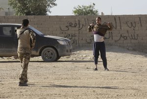 An Iraqi special forces soldier, foreground, asks a man to take off his jacket to check that he is not wearing an explosive belt, in the Al-Samah front line neighborhood, in Mosul, Iraq, Wednesday, Nov. 23, 2016.