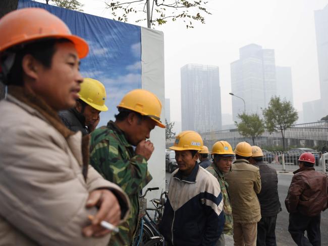 Workers stand outside a construction site on a polluted day in Beijing last week. Picture: Greg Baker/AFP