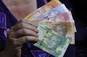 FILE - In this photo taken Tuesday, Nov. 6, 2012, reserve bank governor Gill Marcus displays bank notes bearing the image of former president Nelson Mandela, in Pretoria, South Africa.