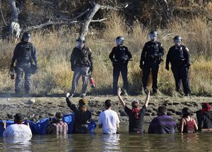 Dozens of protestors demonstrating against the expansion of the Dakota Access Pipeline wade in cold creek waters confronting local police, as remnants of pepper spray waft over the crowd near Cannon Ball, N.D., Wednesday, Nov. 2, 2016.