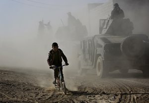 An Iraqi boy rides his bicycle as he follows the special forces Humvees on their way to the front line to battle against Islamic State militants, in the Al-Samah neighborhood in Mosul, Iraq, Wednesday, Nov. 23, 2016.