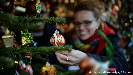 Eine junge Frau sieht sich auf dem Weihnachtsmarkt WeihnachtsZauber auf dem Gendarmenmarkt in Berlin Anhänger für den Weihnachtsbaum an. (Foto: picture alliance/dpa/B.Peders)