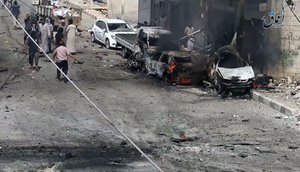 File - This undated image posted online on Thursday, July. 28, 2016, by supporters of the Islamic State militant group on an anonymous photo sharing website, shows Syrian citizens gathered near burned cars after airstrikes hit Manbij, in Aleppo province, Syria.