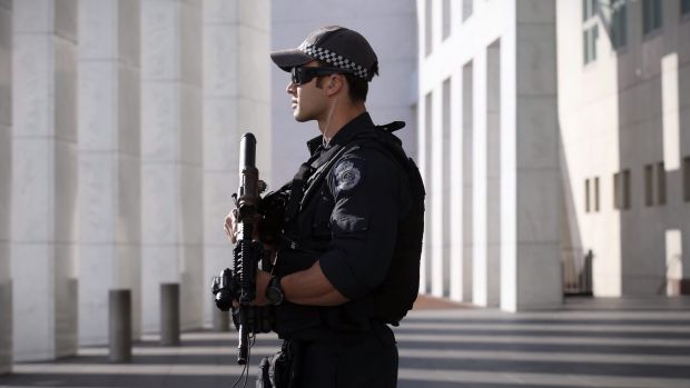 An AFP officer armed with an SR-16 stands guard to the front of Parliament House.