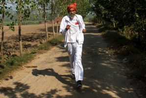Dharam Pal Singh, a herder who regularly runs and claims to be 119 years old, trains on a dirt road near his home in the ...